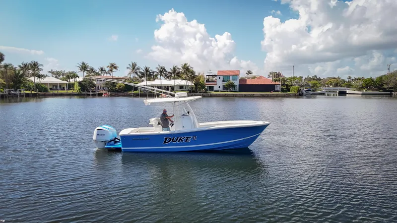 Slide: The Image of 2019 Regulator 25 boat on calm water, clear sky, and waterfront homes in the background. - 1