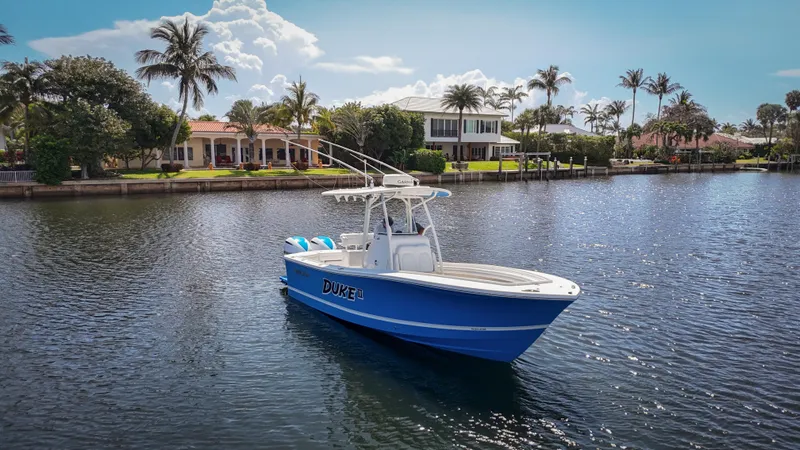 Slide: The Image of 2019 Regulator 25 boat on a serene waterway, surrounded by palm trees and luxury homes. - 11