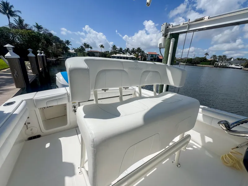 Slide: The Image of 2019 Regulator 25 boat interior with white seating, docked by a scenic waterfront. - 16