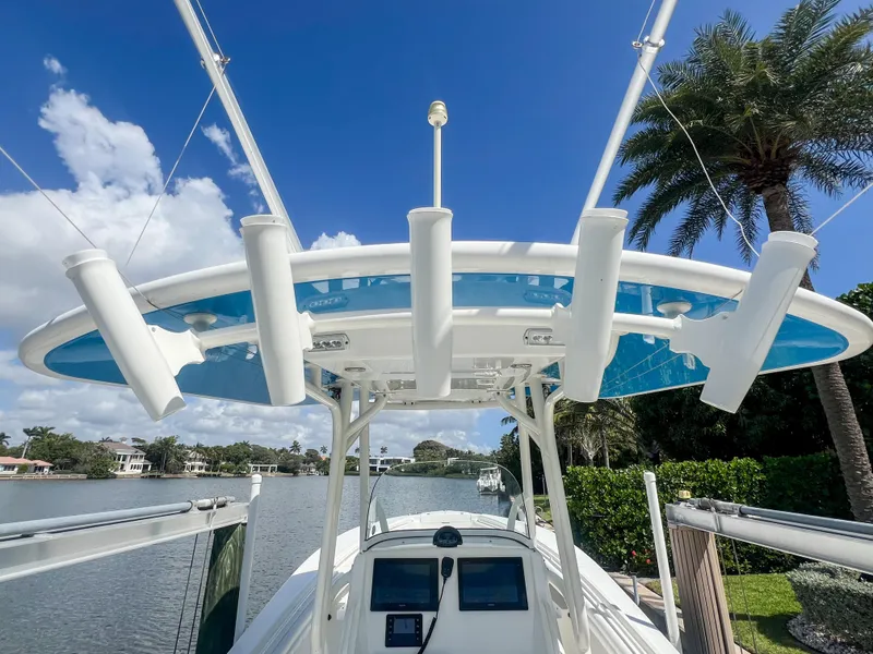Slide: The Image of 2019 Regulator 25 boat with rod holders, docked by a scenic waterfront. - 25