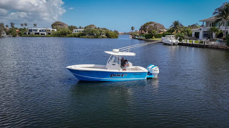 Slide: The Image of 2019 Regulator 25 boat on a calm waterway, surrounded by lush greenery and waterfront homes. - 6