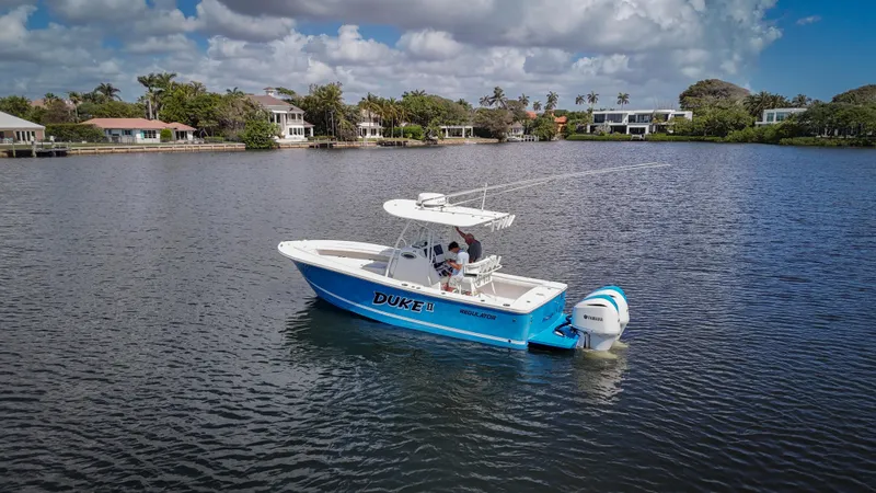Slide: The Image of 2019 Regulator 25 boat on a calm lake with houses in the background. - 7