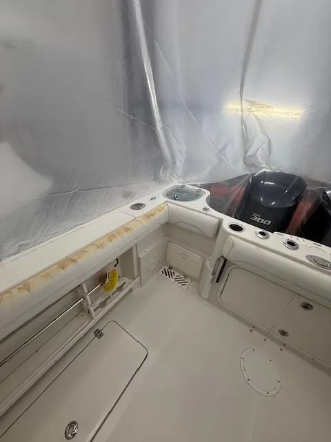 Slide: The Image of 2015 Sailfish 290 CC boat interior with motor, featuring storage compartments and rod holders. - 12