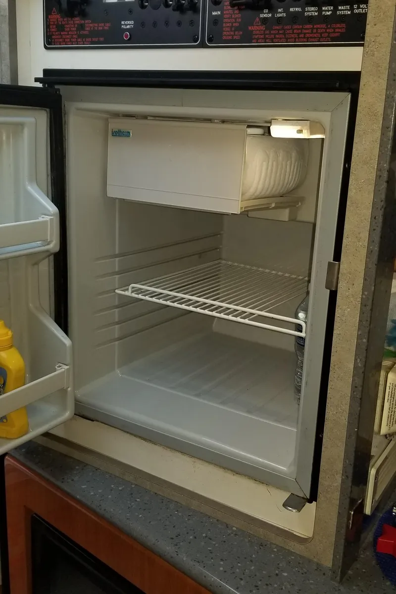 Slide: The Image of Small refrigerator with open door, showing empty shelves and mustard bottle inside. - 18