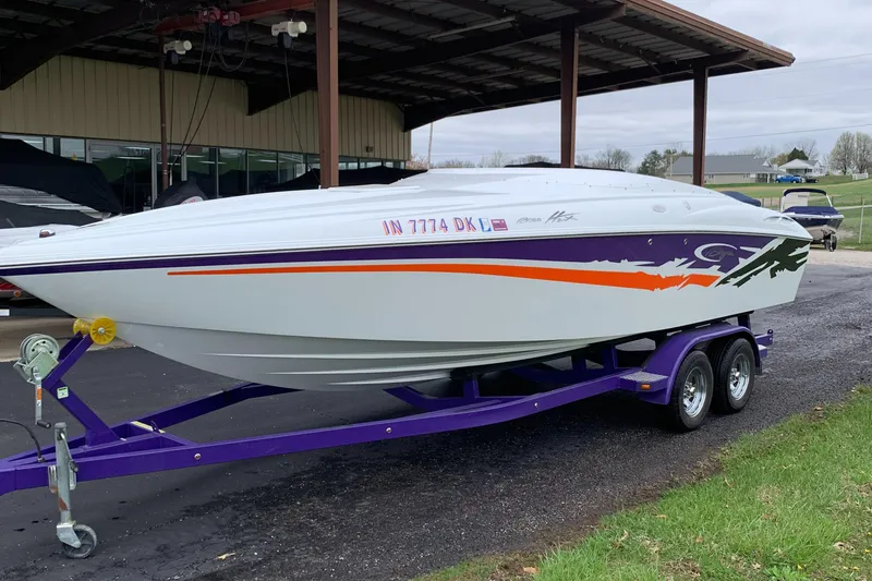 Slide: The Image of 2003 Baja 24 H2X Boss speedboat on a purple trailer, parked outdoors. - 2