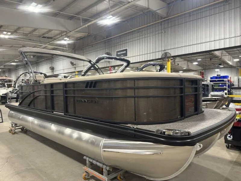 Slide: The Image of 2025 Bennington SX L-Bench 23 SXL pontoon boat in a warehouse setting. - 1