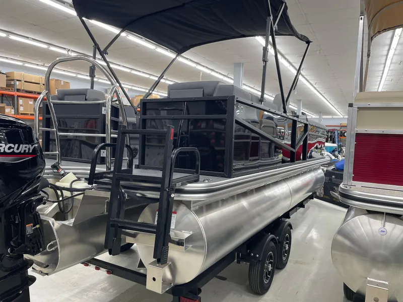 Slide: The Image of 2025 Lowe LS230W pontoon boat displayed indoors with canopy and Mercury engine. - 4