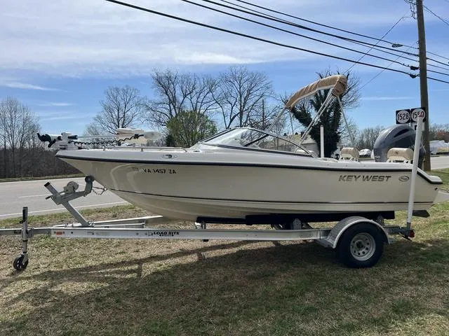 Slide: The Image of 2018 Key West 186DC boat on trailer, parked on grass near roadside. - 2