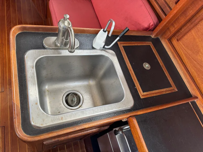 Slide: The Image of 1981 Bristol 29.9 yacht kitchen sink with faucet, wooden countertop, and red cushion. - 21