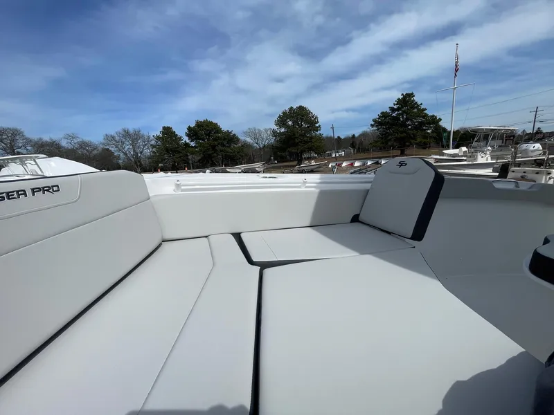 Slide: The Image of 2025 Sea Pro 245 Sandbar boat interior with cushioned seating under a blue sky. - 33