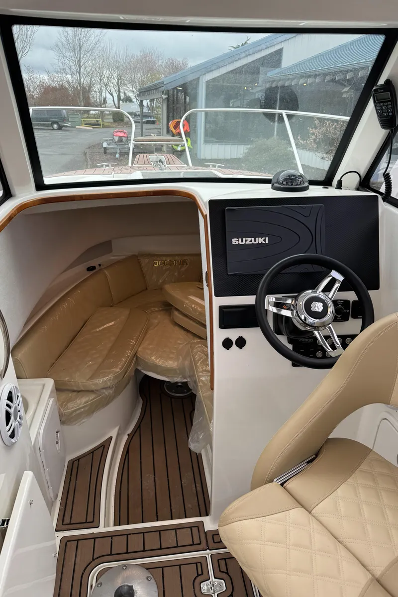 Slide: The Image of Interior of a 2022 Oceania 23WA boat with beige seating and Suzuki steering. - 7