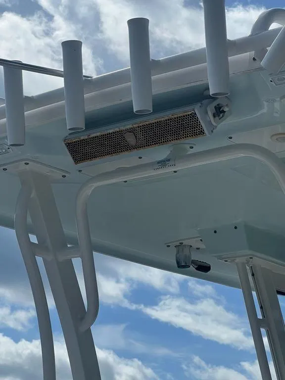 Slide: The Image of 2018 Robalo R302 boat T-top with rod holders against a cloudy sky. - 12