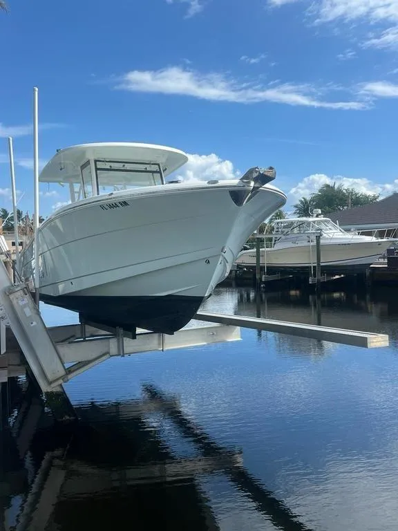 Slide: The Image of 2018 Robalo R302 boat on lift by waterfront under blue sky. - 3