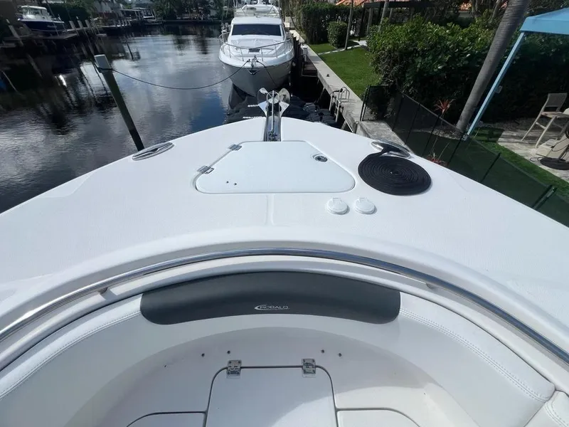 Slide: The Image of 2018 Robalo R302 boat bow view at dock, featuring sleek design and calm water. - 5