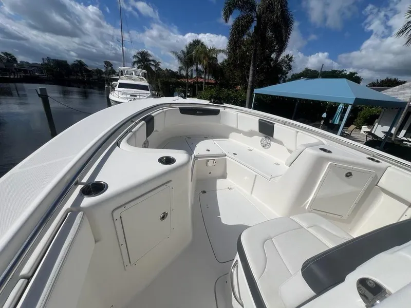 Slide: The Image of 2018 Robalo R302 boat interior with white seating and storage compartments, docked near palm trees. - 7
