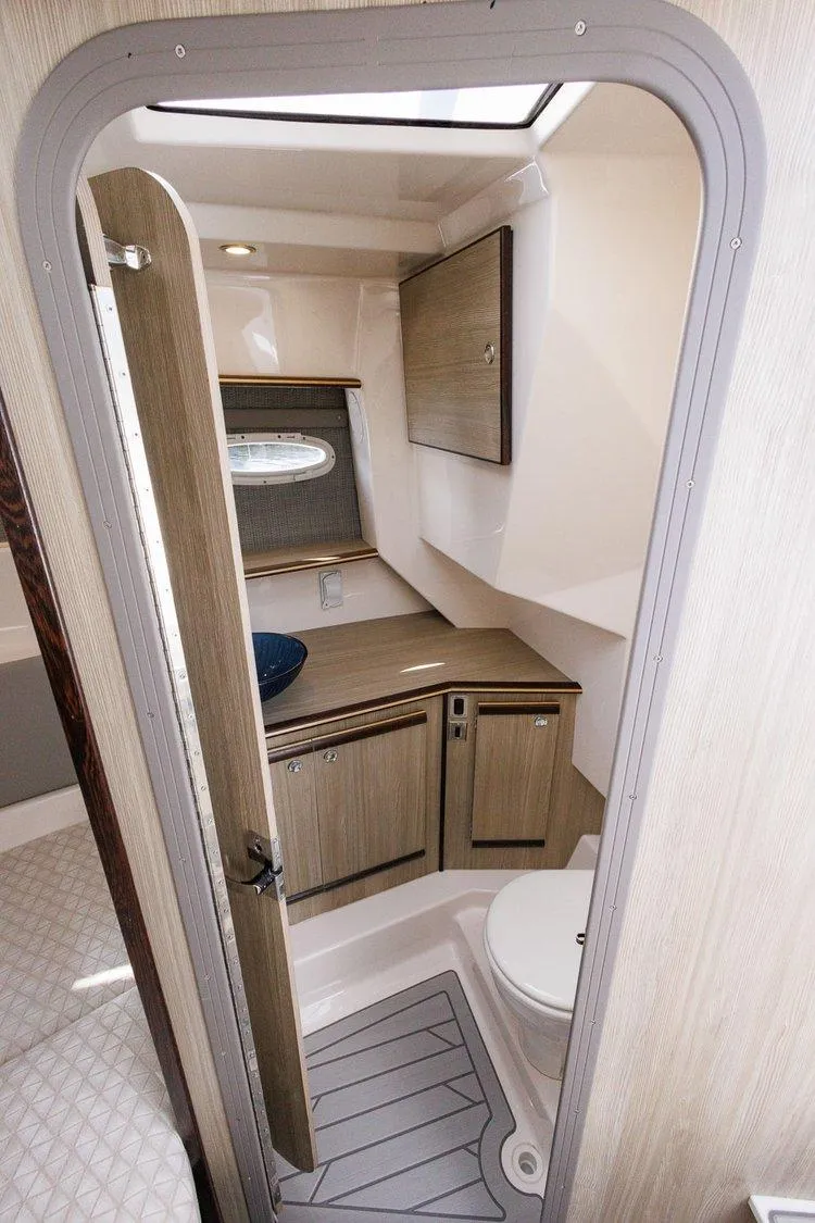 Slide: The Image of 2026 Solara S 310 SB boat interior bathroom with modern fixtures and wood accents. - 16