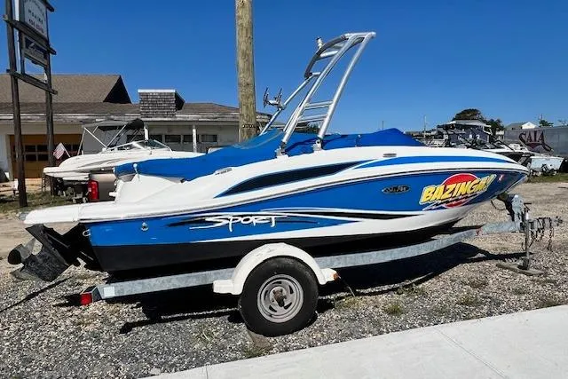Slide: The Image of 2011 Sea Ray 185 Sport boat on trailer, blue and white design, parked outdoors. - 0