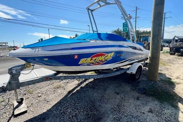 Slide: The Image of 2011 Sea Ray 185 Sport boat with blue cover on trailer, parked outdoors. - 1