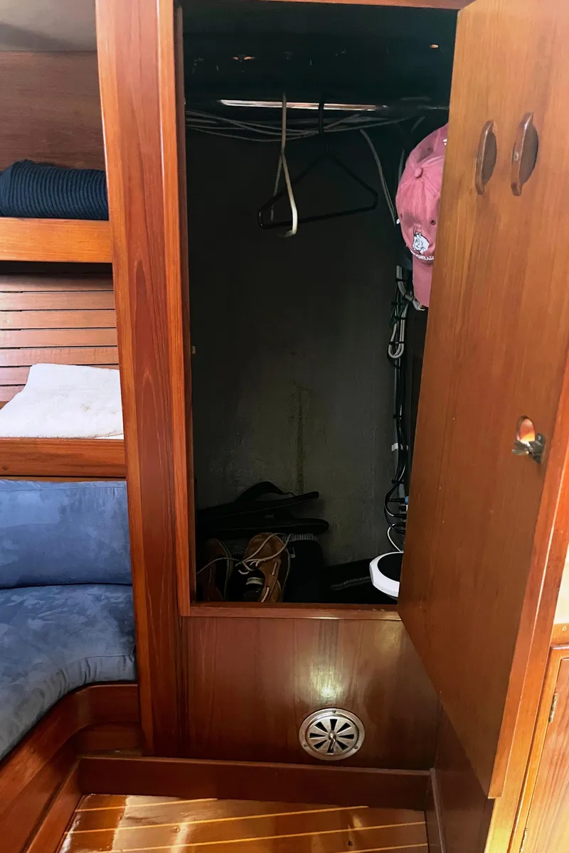 Slide: The Image of Wooden closet interior on a 1982 Baltic 42 sailboat, featuring shelves and hanging space. - 25