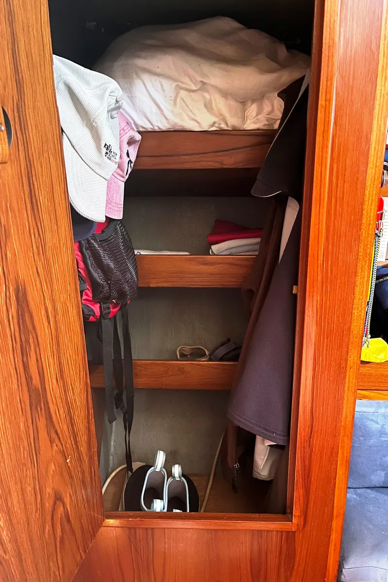 Slide: The Image of Wooden closet interior with shelves, clothing, and accessories on a 1982 Baltic 42 sailboat. - 27