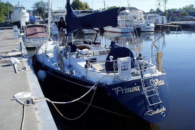 Slide: The Image of 1982 Baltic 42 sailboat docked at marina, named "Primera Vista," with blue hull and covered sails. - 4