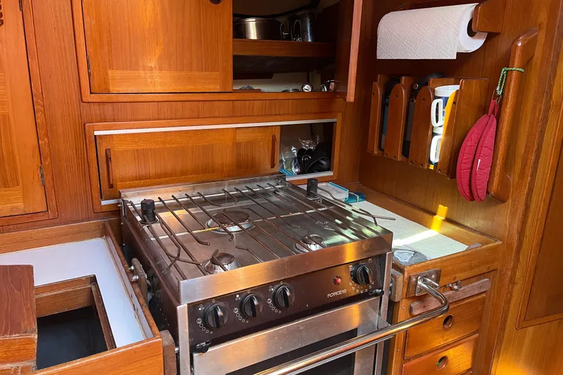 Slide: The Image of Galley kitchen in 1982 Baltic 42 sailboat with stove, wooden cabinetry, and storage. - 45