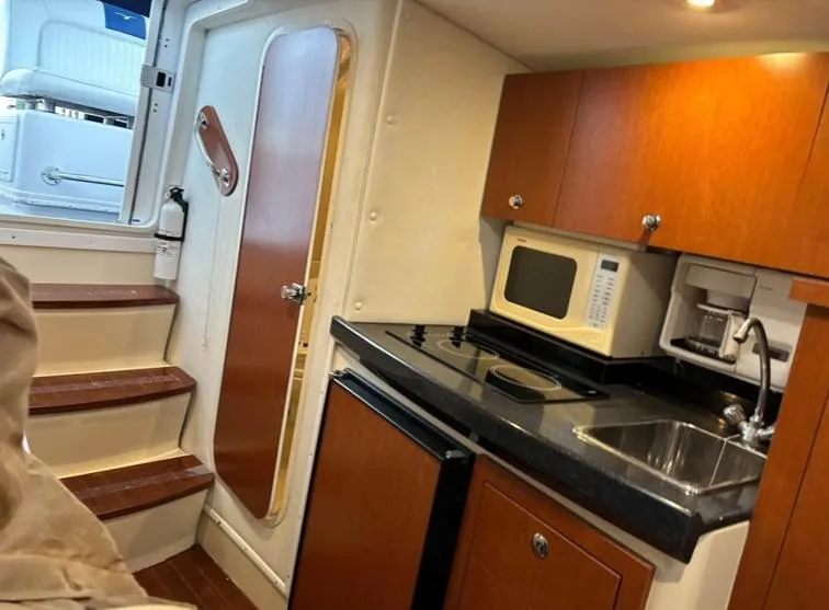 Slide: The Image of 2005 Pro-Line 33 Express cabin with kitchenette, featuring microwave, sink, and stairs. - 6
