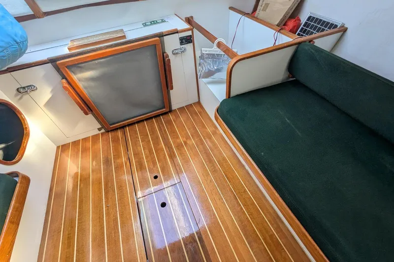 Slide: The Image of Interior of 1992 Alerion Express 28 sailboat with wooden flooring and green seating. - 32