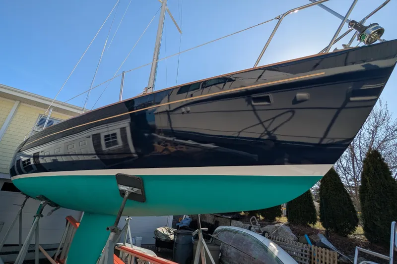 Slide: The Image of 2012 Alerion Express 28 sailboat on stands, featuring a sleek black hull and turquoise bottom. - 4