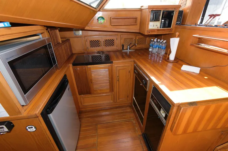 Slide: The Image of 1988 Symbol 55 Cockpit Motor Yacht kitchen with wood cabinetry, microwave, and mini fridge. - 16