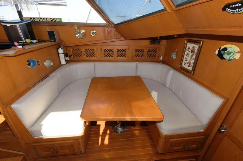 Slide: The Image of Cozy dining area in 1988 Symbol 55 Cockpit Motor Yacht with wooden table and cushioned seating. - 17
