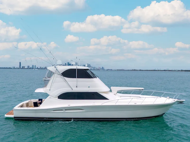 Slide: The Image of 2008 Riviera 51 Enclosed Bridge yacht on calm blue water under a partly cloudy sky. - 0