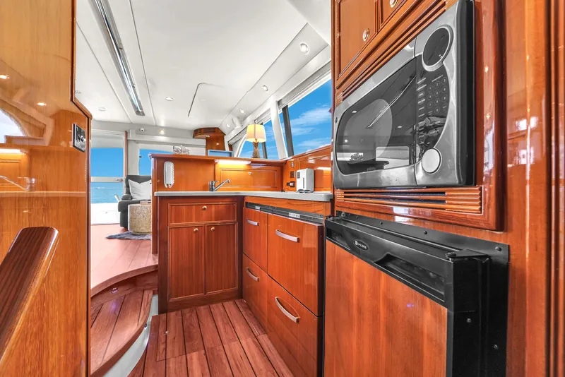 Slide: The Image of Luxurious 2008 Riviera 51 Enclosed Bridge yacht kitchen with wood cabinetry and modern appliances. - 33