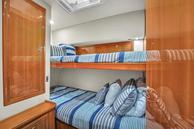 Slide: The Image of 2008 Riviera 51 Enclosed Bridge cabin with bunk beds and striped bedding. - 43