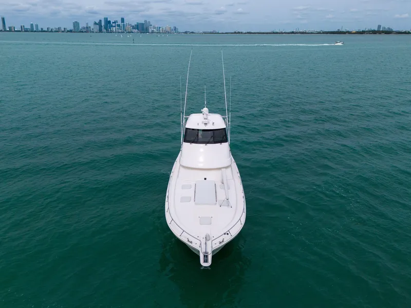 Slide: The Image of 2008 Riviera 51 Enclosed Bridge yacht cruising on open water with city skyline in background. - 8