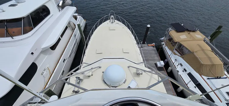 Slide: The Image of 1979 Hatteras 60 Enclosed Bridge Convertible yacht docked between two boats. - 15