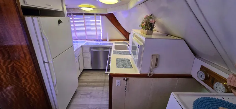 Slide: The Image of 1979 Hatteras 60 Enclosed Bridge Convertible yacht kitchen with modern appliances and wood accents. - 27