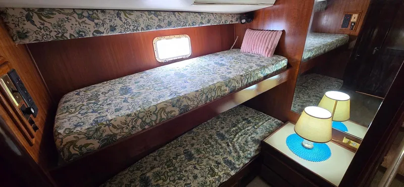 Slide: The Image of 1979 Hatteras 60 Enclosed Bridge Convertible cabin with bunk beds and floral decor. - 29