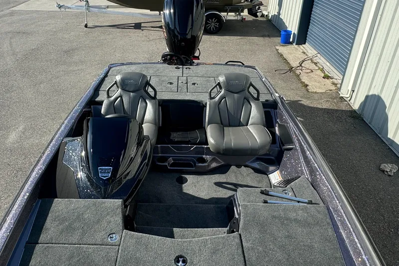 Slide: The Image of 2025 Skeeter ZXR20SE boat interior with dual seats and motor, parked near a garage. - 10