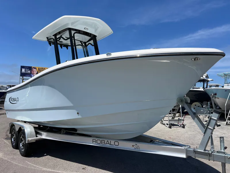 The Image of 2025 Robalo R232 Explorer boat on trailer under clear blue sky. - 0