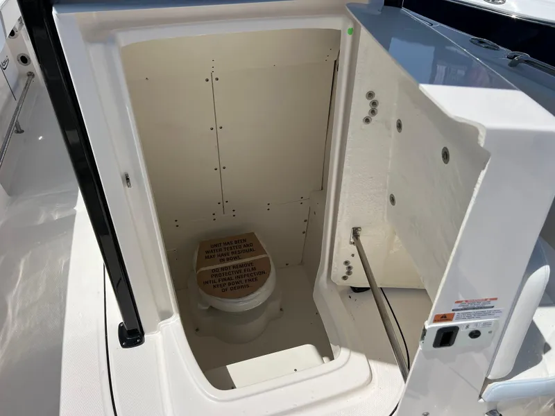 Slide: The Image of 2025 Robalo R232 Explorer boat interior with open storage compartment and toilet. - 14
