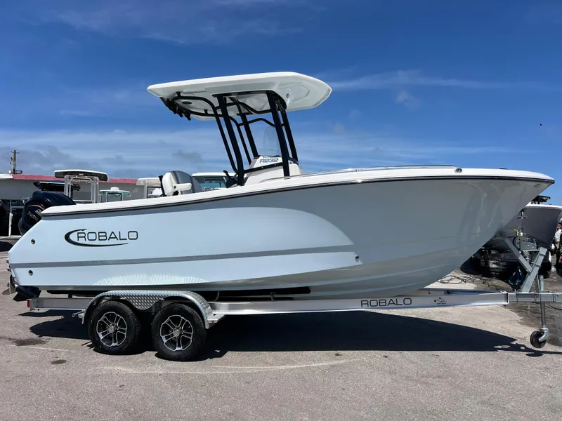 Slide: The Image of 2025 Robalo R232 Explorer boat on trailer, side view under clear blue sky. - 2