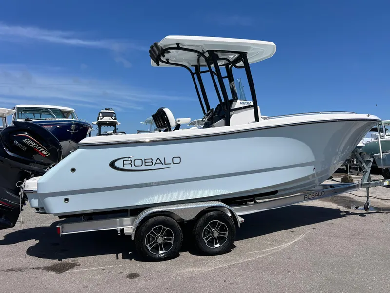 Slide: The Image of 2025 Robalo R232 Explorer boat on trailer, side view, under clear blue sky. - 3