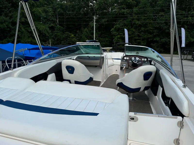 Slide: The Image of 2006 Regal 2200 Bowrider boat with white seating and blue accents, parked outdoors. - 13