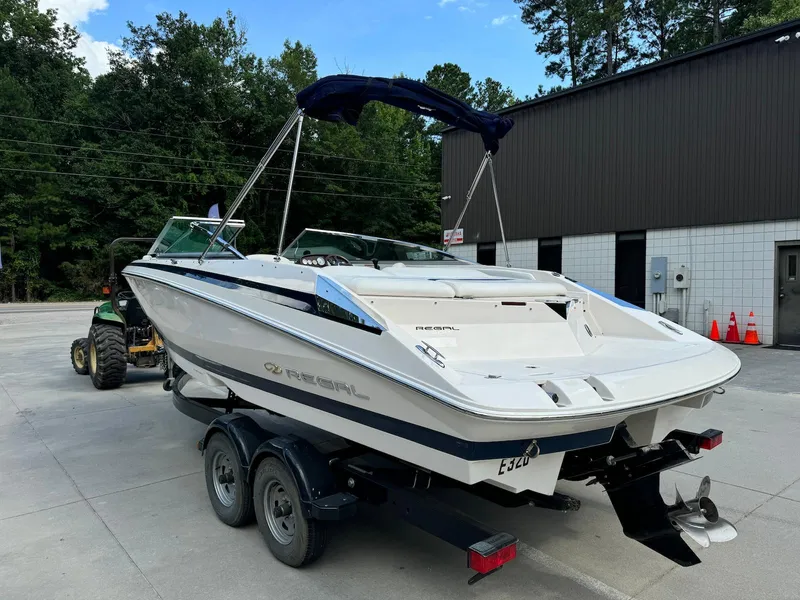 Slide: The Image of 2006 Regal 2200 Bowrider boat on trailer, parked outdoors near a building. - 4