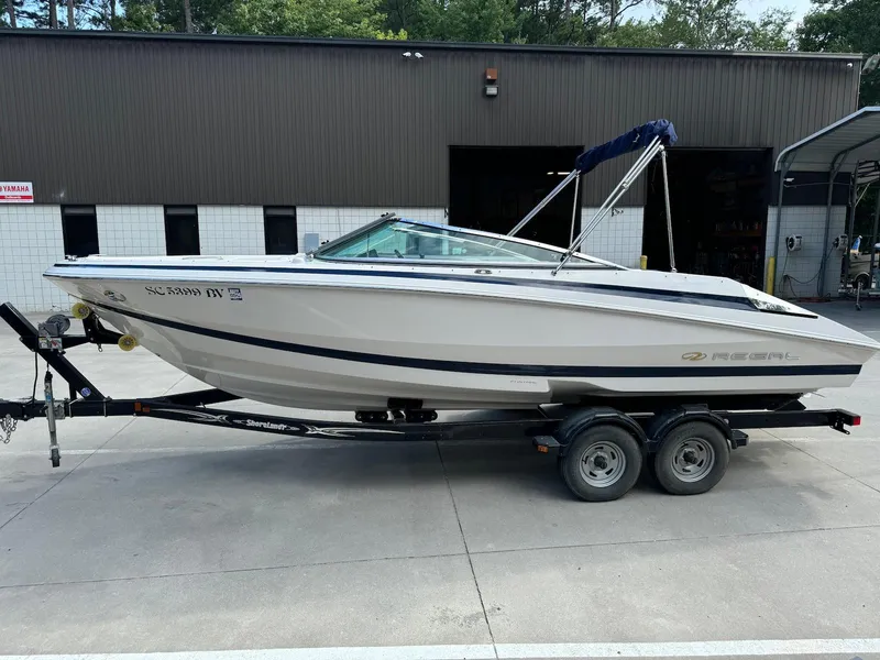 Slide: The Image of 2006 Regal 2200 Bowrider boat on trailer, parked outside a building. - 5