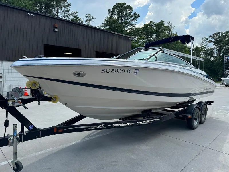 Slide: The Image of 2006 Regal 2200 Bowrider boat on trailer, parked outdoors near a building. - 6