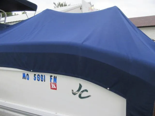 Slide: The Image of Covered 2009 JC 26' Tritoon boat with blue tarp and visible registration numbers. - 11