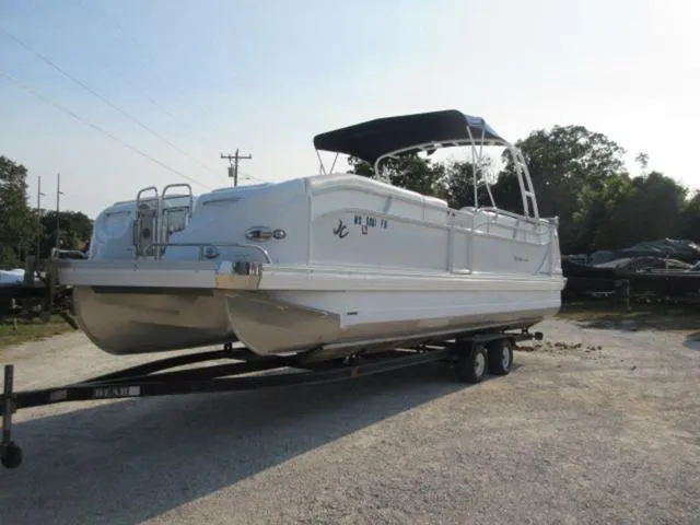 Slide: The Image of 2009 JC 26' Tritoon boat with 300Hp Evinrude outboard on trailer, parked outdoors. - 15