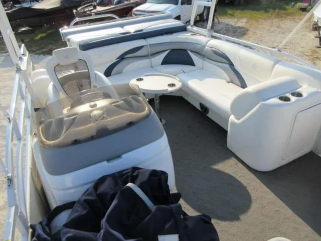 Slide: The Image of 2009 JC 26' Tritoon boat interior with white seating and table, featuring 300Hp Evinrude outboard. - 23